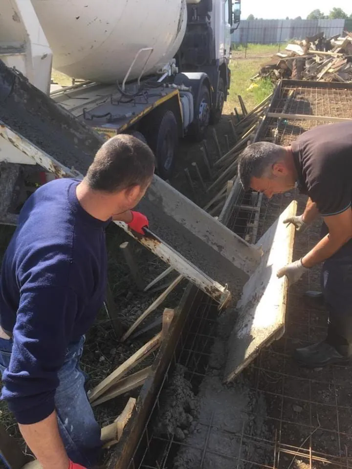 Two helpers carrying a formwork panel.