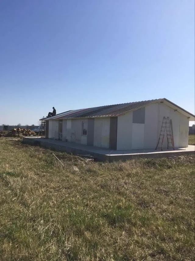 The main building of the Cheerful Kindergarten standing in the field, roof finished.