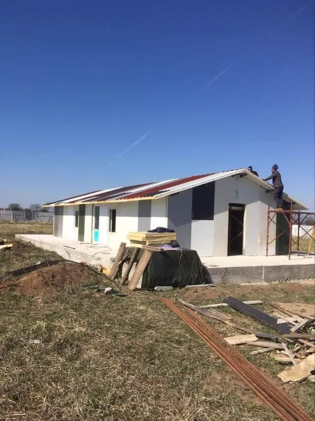 The corner of the building with materials under a tarp.