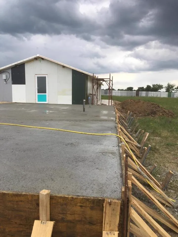 A worker levels the freshly poured concrete base.