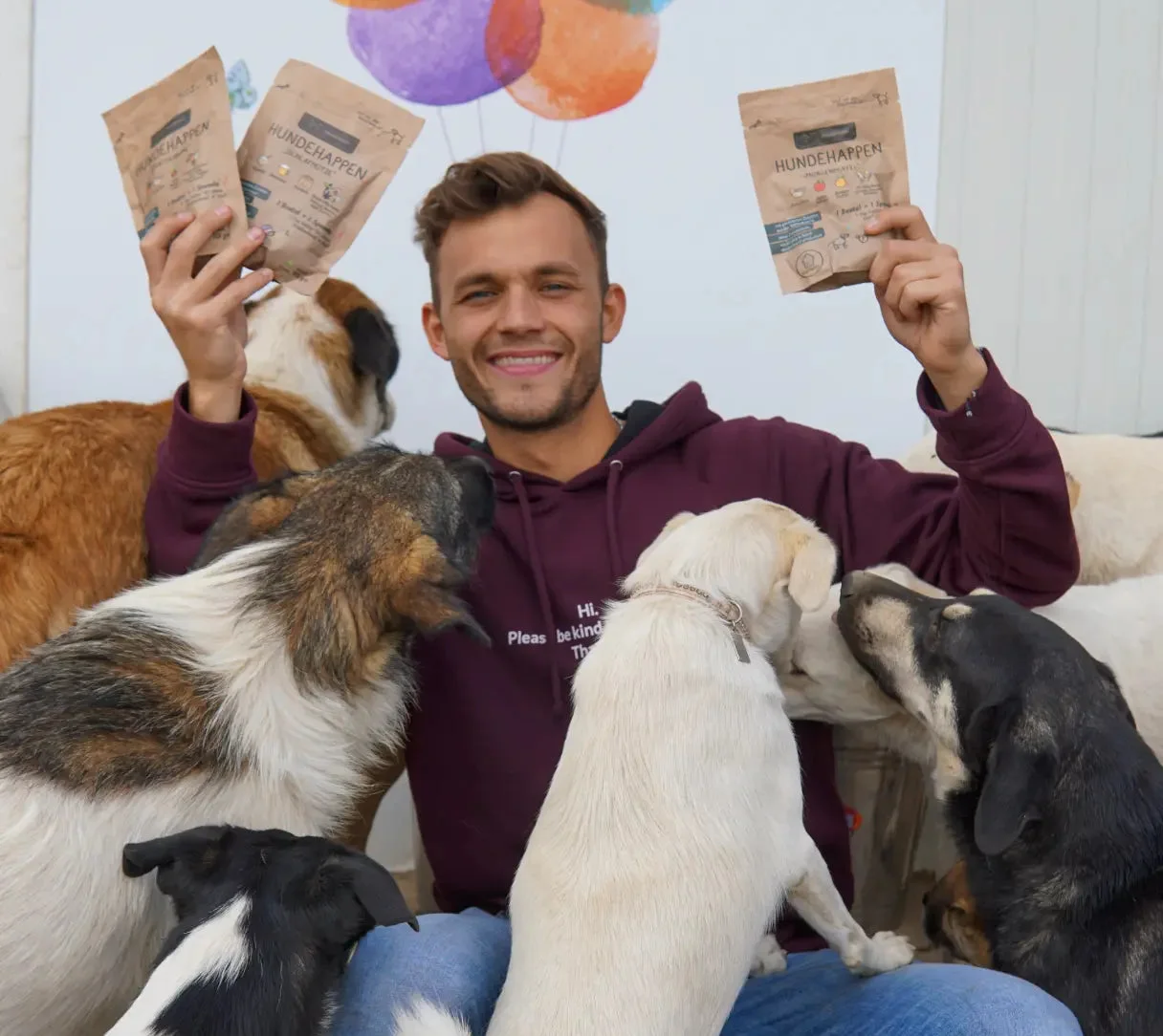 One of the founders holding Hunderunde snack bags, surrounded by dogs.