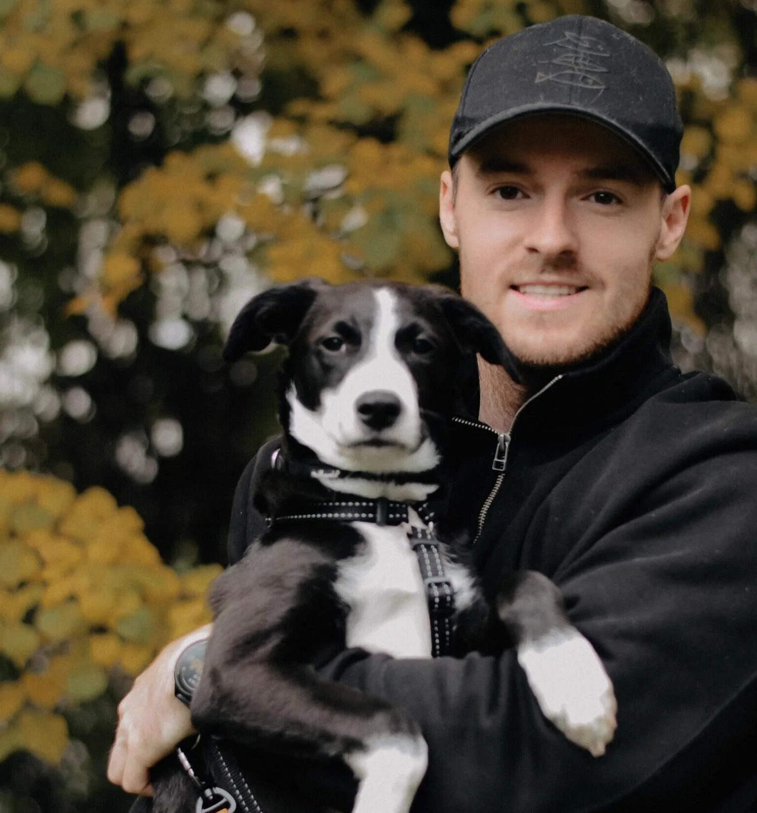 A helper holding a black and white dog in his arms.